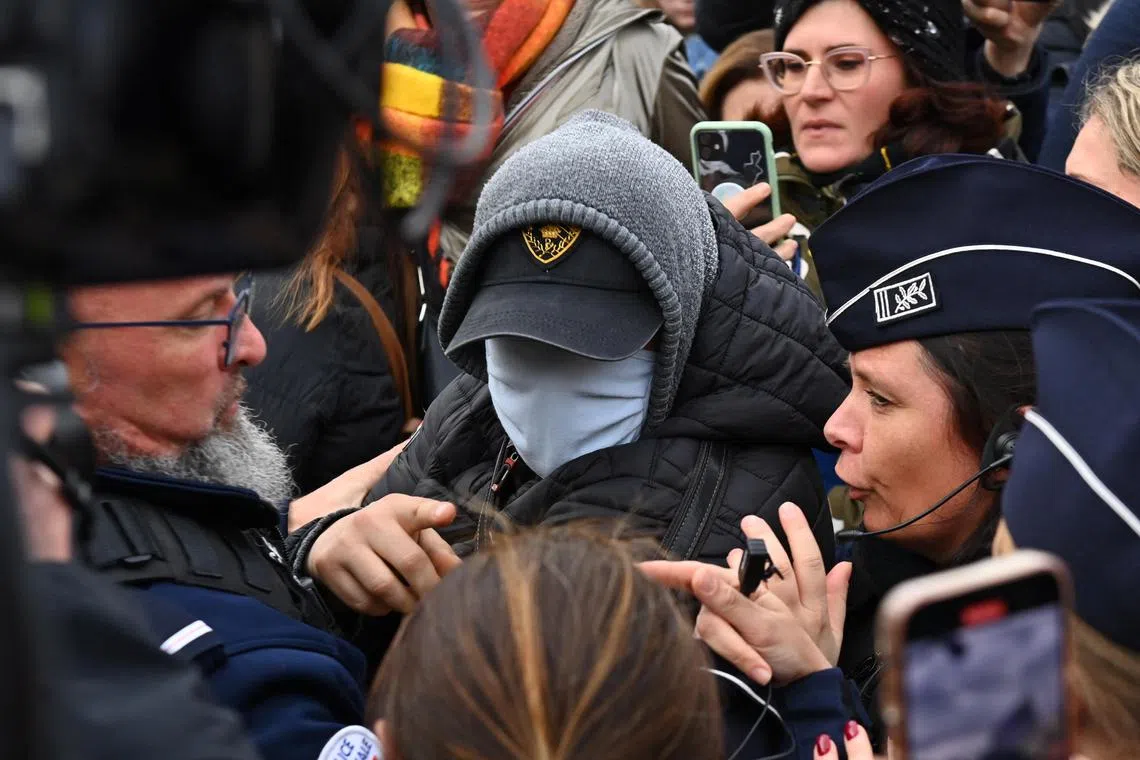 A man hiding his face is surrounded by French police, journalists and protesters, as he leaves court following the verdict in the Dominique Pelicot trial on Dec 19.