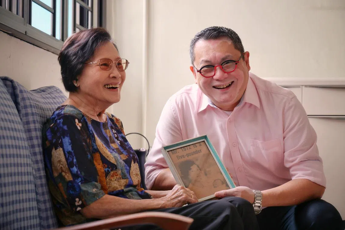 Mr Daniel Cheong, the first baby born in Singapore in 1972, and his mother, Madam Lee, with a framed clipping of The Straits Times talking about his birth.