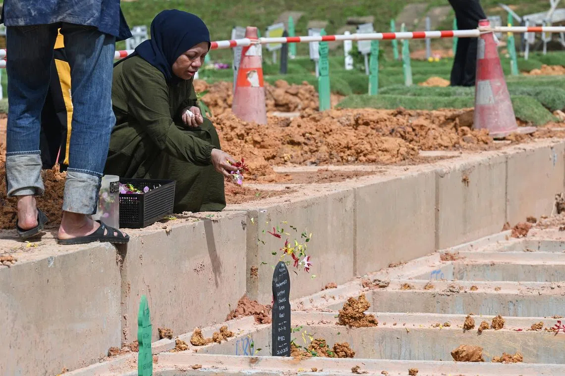 Madam Siti, the mother of the 13-year-old boy who died after falling into the Kallang River, sprinkling flowers over his grave on Feb 27.