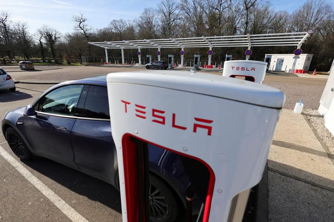 FILE PHOTO: A driver recharges the battery of his Tesla car, at a Tesla Super Charging station, in a petrol station on the highway in Chateauvillain, France, February 20, 2023. REUTERS/Pascal Rossignol/File Photo