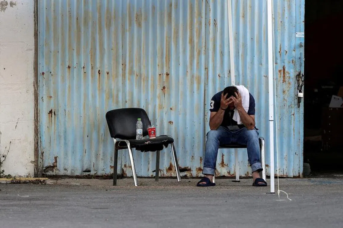 FILE PHOTO: A migrant who was rescued at open sea off Greece along with other migrants, after their boat capsized, reacts outside a warehouse used as a shelter, at the port of Kalamata, Greece, June 15, 2023. REUTERS/Stelios Misinas/File Photo