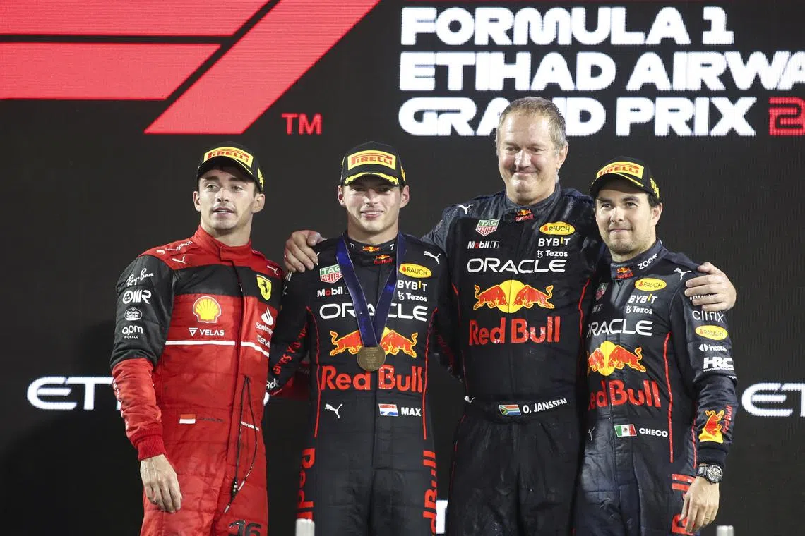 From left: Charles Leclerc of Ferrari, world champion  Max Verstappen of Red Bull Racing, a Red Bull official and Sergio Perez pose on the podium following the  Abu Dhabi Grand Prix on Sunday. 