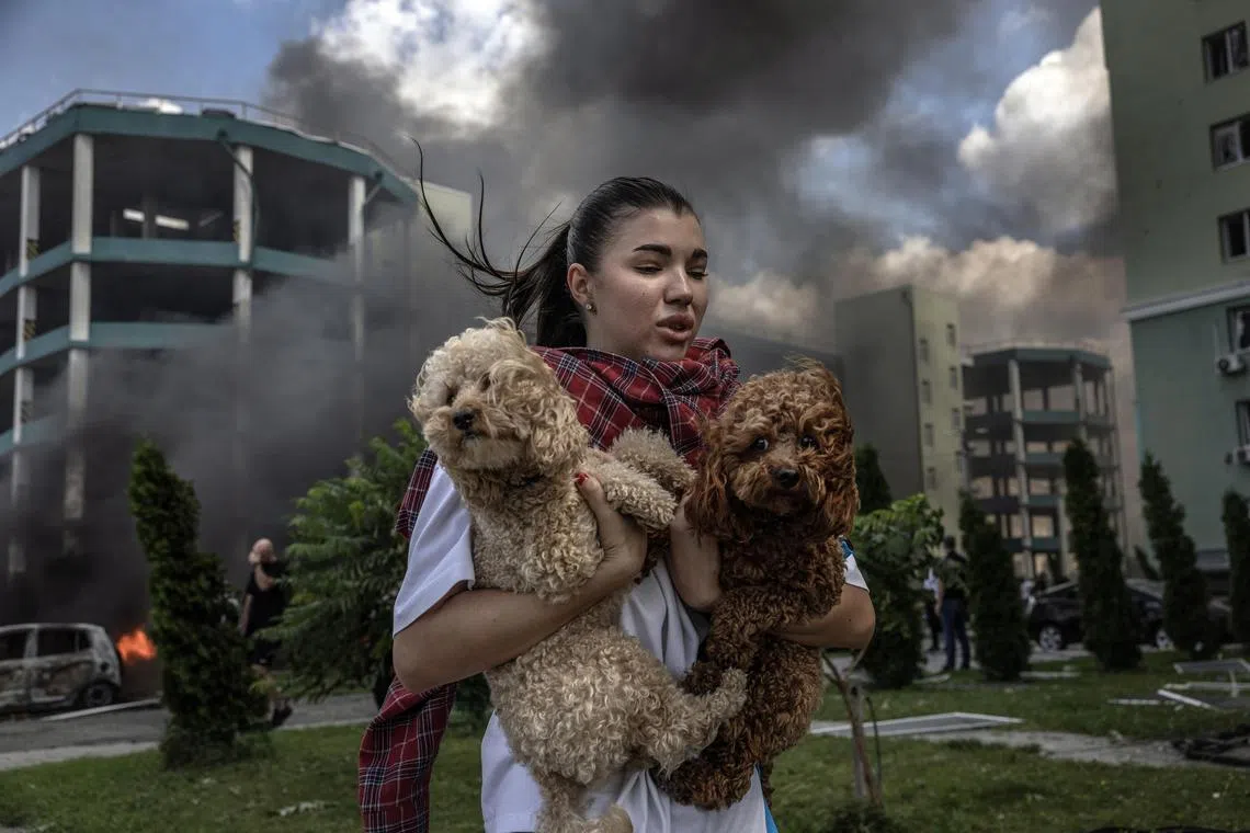 A woman carrying her pet dogs as she flees her home, following a Russian bomb attack on an apartment building in Kharkiv, Ukraine, on July 24.