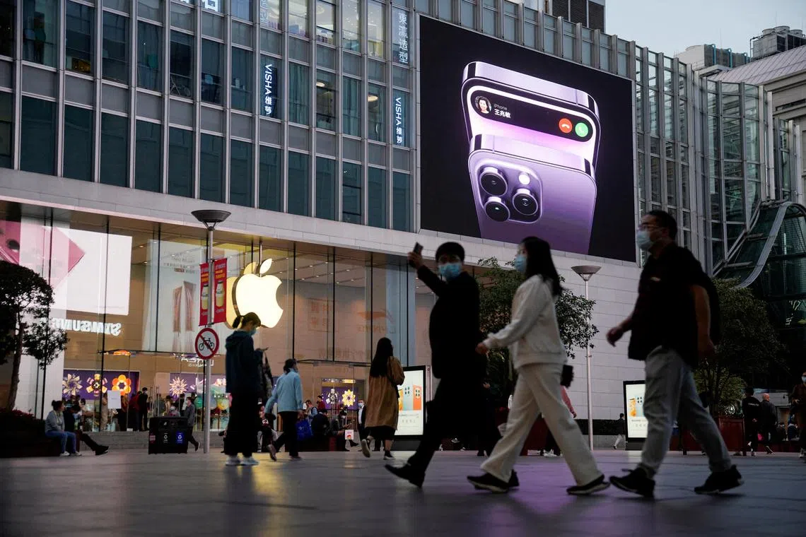 People walk near a display advertising the iPhone 14 in Shanghai.