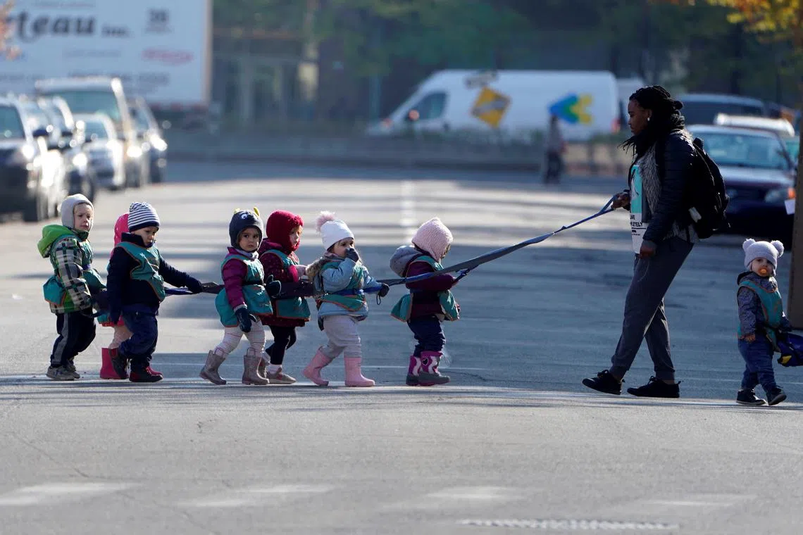 FILE PHOTO: A guardian escorts children on a tether while walking across a road in the Papineau area of Montreal, Quebec, Canada, October 21, 2019. REUTERS/Carlo Allegri/File Photo