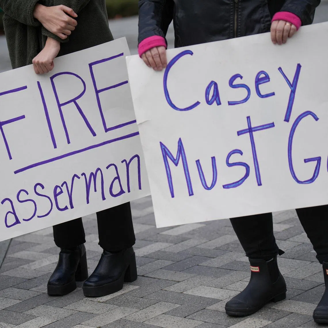 People hold placards on the day local elected officials, survivors and activists hold a press conference calling for the removal of Casey Wasserman as head of the LA Olympic Committee following revelations of his ties to Ghislaine Maxwell, in Los Angeles, California, U.S., February 17, 2026. REUTERS/Daniel Cole