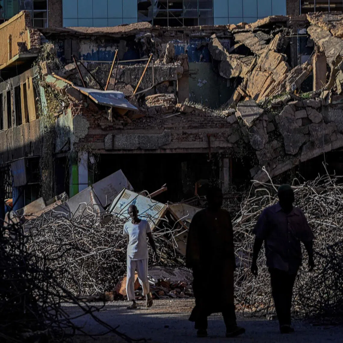 Sudanese men walk past a destroyed building in the capital Khartoum on April 16.