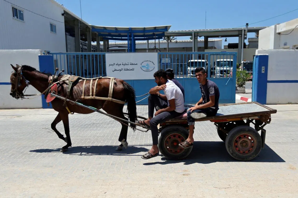 FILE PHOTO: Palestinians ride a horse-drawn cart past Gaza desalination plant, in the central Gaza Strip June 23, 2019. REUTERS/Ibraheem Abu Mustafa/File Photo