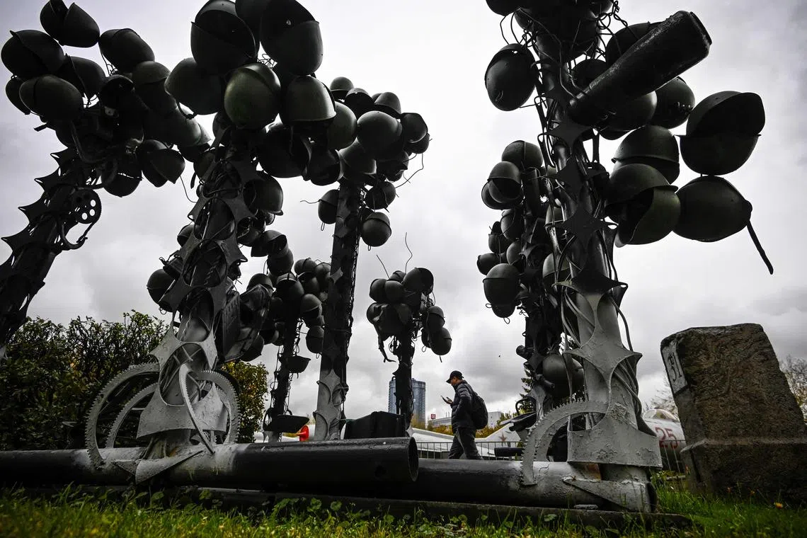 A man walks by a monument to late Russian soldiers made of helmets in the central Museum of Russia's Armed Forces.