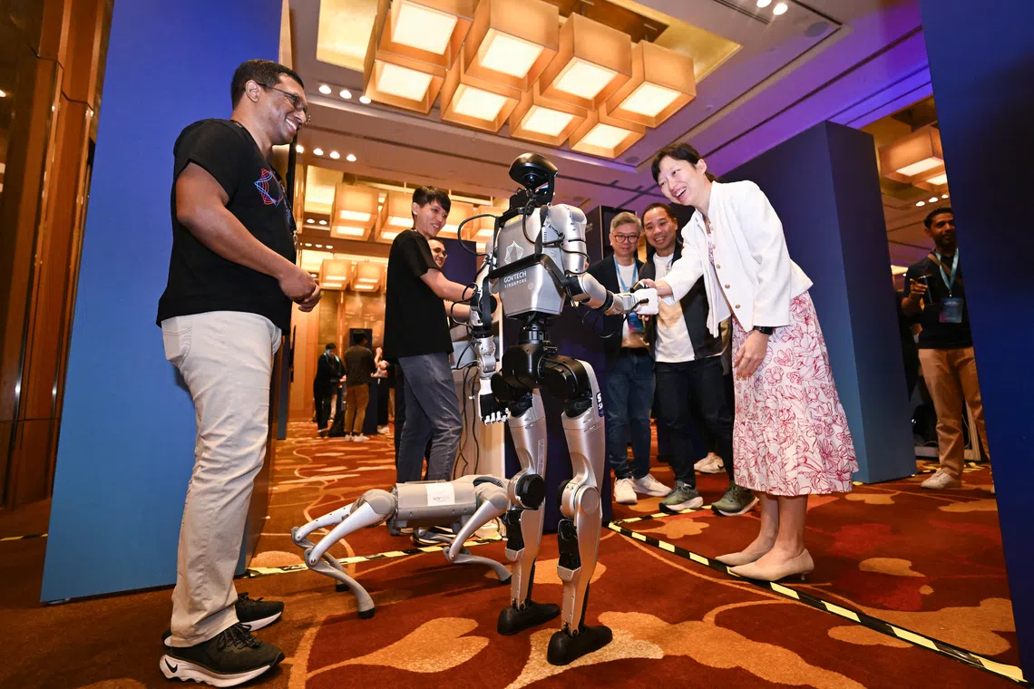 Minister of State for Digital Development and Information Jasmin Lau (right) interacting with a humanoid robot during GovTech Innovation Day 2025 at Marina Bay Sands Expo & Convention Centre on Nov 13.