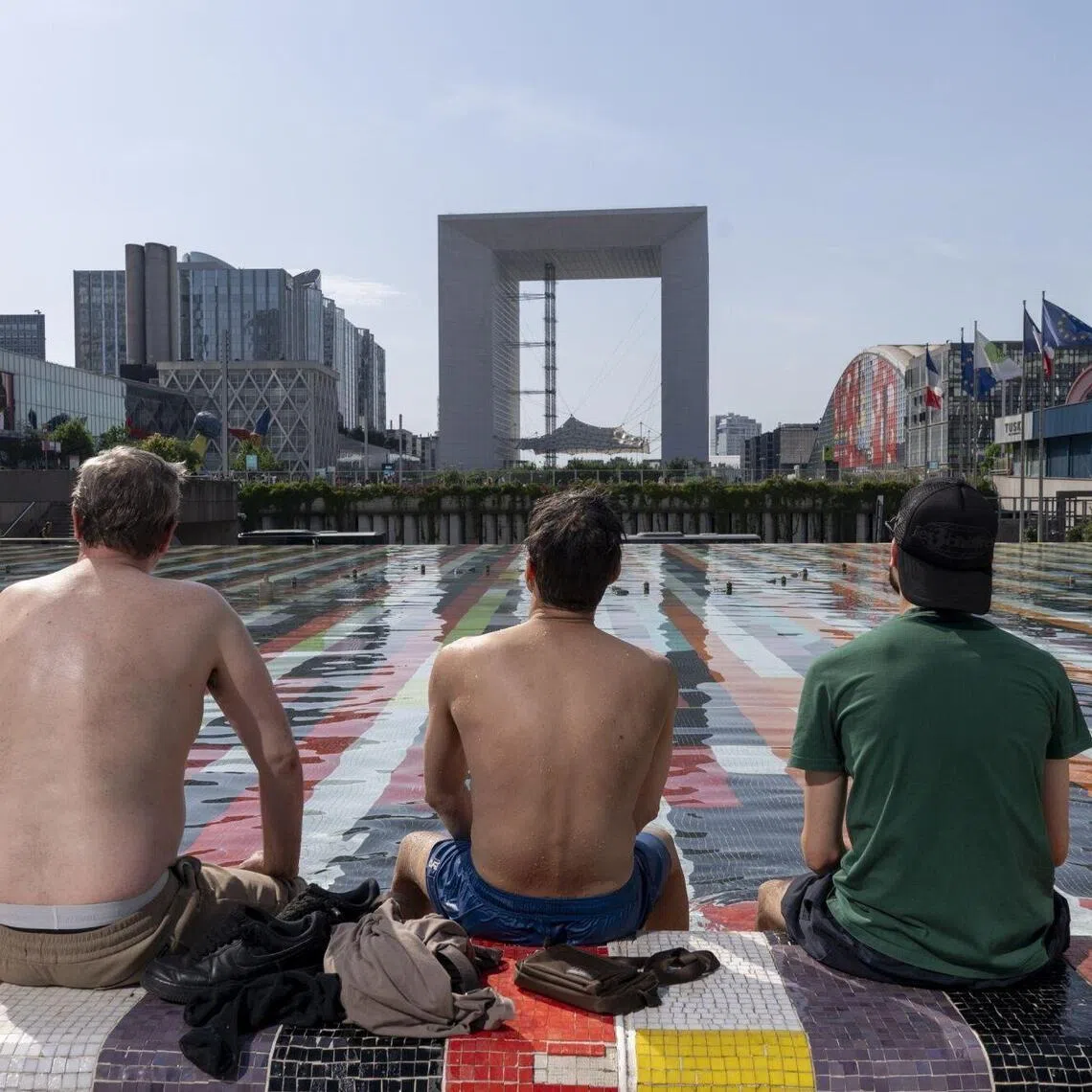 Workers cool themselves amid scorching heat at Fontaine d'Agam at the La Defense business district in Paris.
