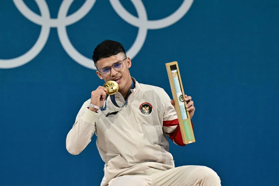 Indonesia's Rizki Juniansyah poses on the podium after winning the men's 73kg weightlifting title at the Paris Olympics.