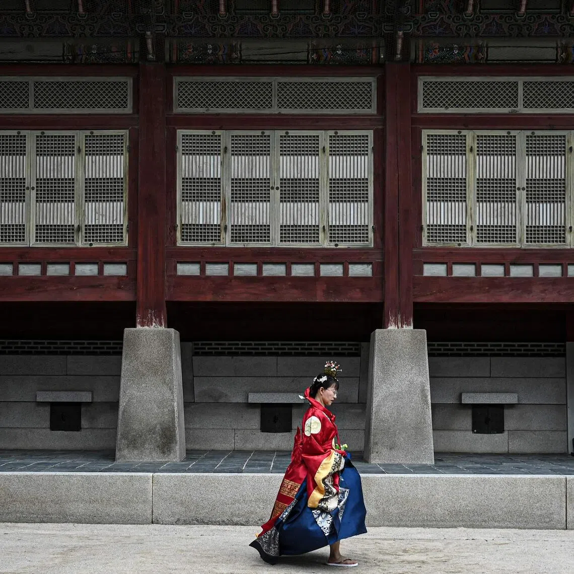 A visitor dressed in a traditional Hanbok dress walks at the Gyeongbokgung Palace in Seoul on June 21, 2026..