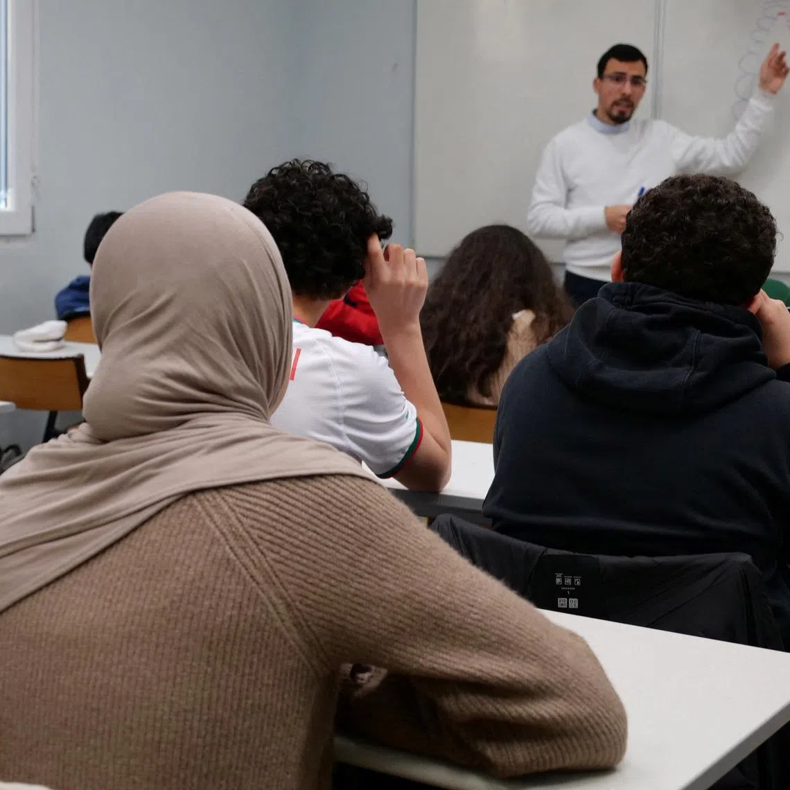 FILE PHOTO: Middle school students, some wearing a hijab, listen to teacher Ilyas Laarej during an Islamic ethics class at the Averroes school, France's biggest Muslim educational institution that has lost its state funding on grounds of administrative failures and questionable teaching practises, in Lille, France, March 19, 2024. REUTERS/Ardee Napolitano/File Photo