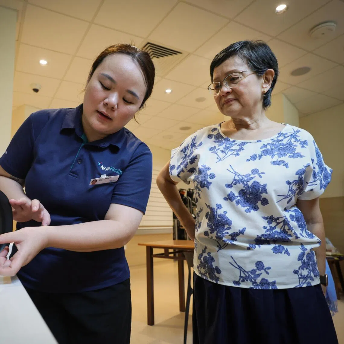 Retired teacher Wong (right) being trained by TTSH senior staff nurse Annie Ling on how to hydrate her mother to prevent delirium.