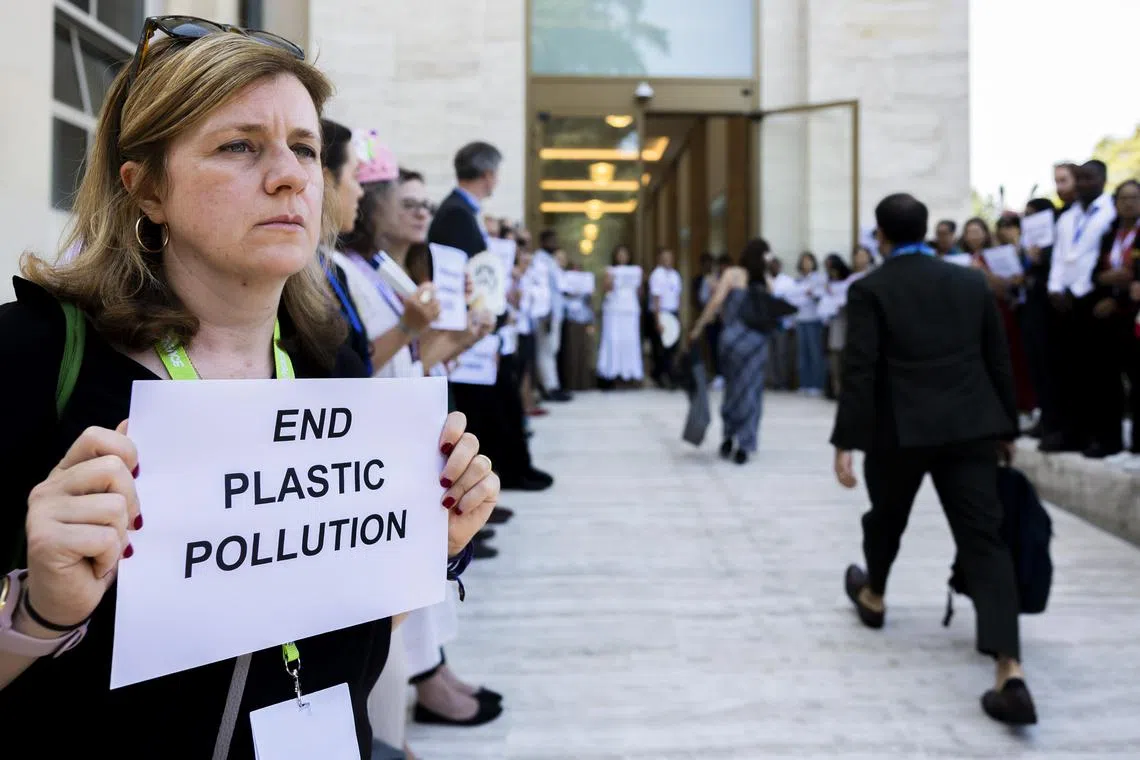 Protesters welcoming delegates with placards at the UN plastics treaty talks in Geneva, Switzerland, on Aug 9.