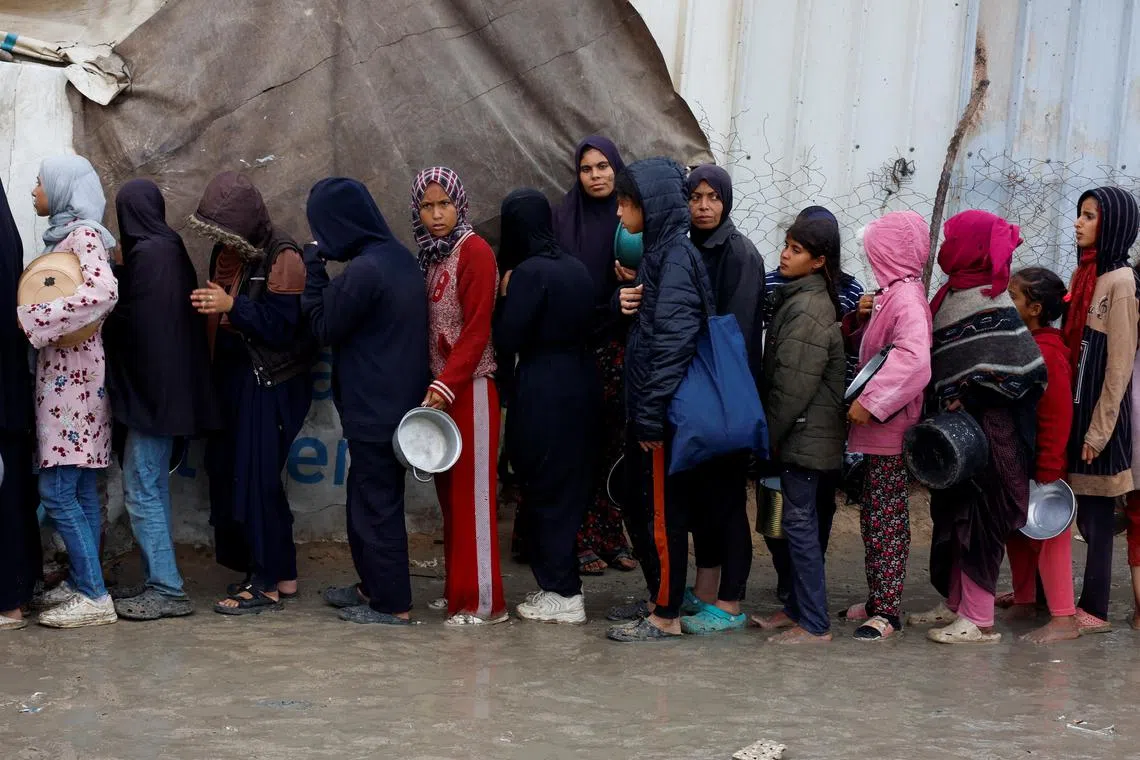 Palestinians queue to receive food cooked by a charity kitchen, amid a hunger crisis, as the Israel-Hamas conflict continues, in Khan Younis, southern Gaza Strip, November 24, 2024. REUTERS/Mohammed Salem