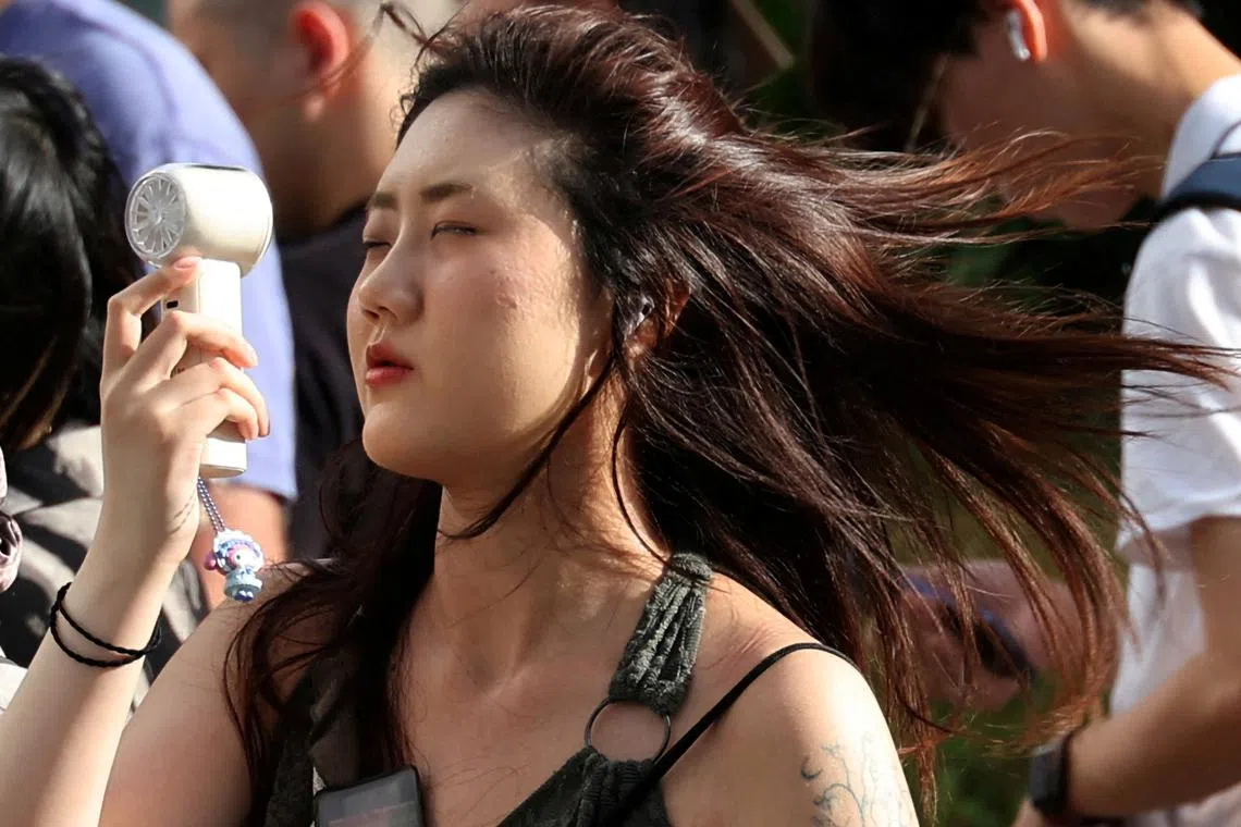 A woman using a portable fan to cool herself during a heatwave in Tokyo, Japan, on July 17, 2025. 