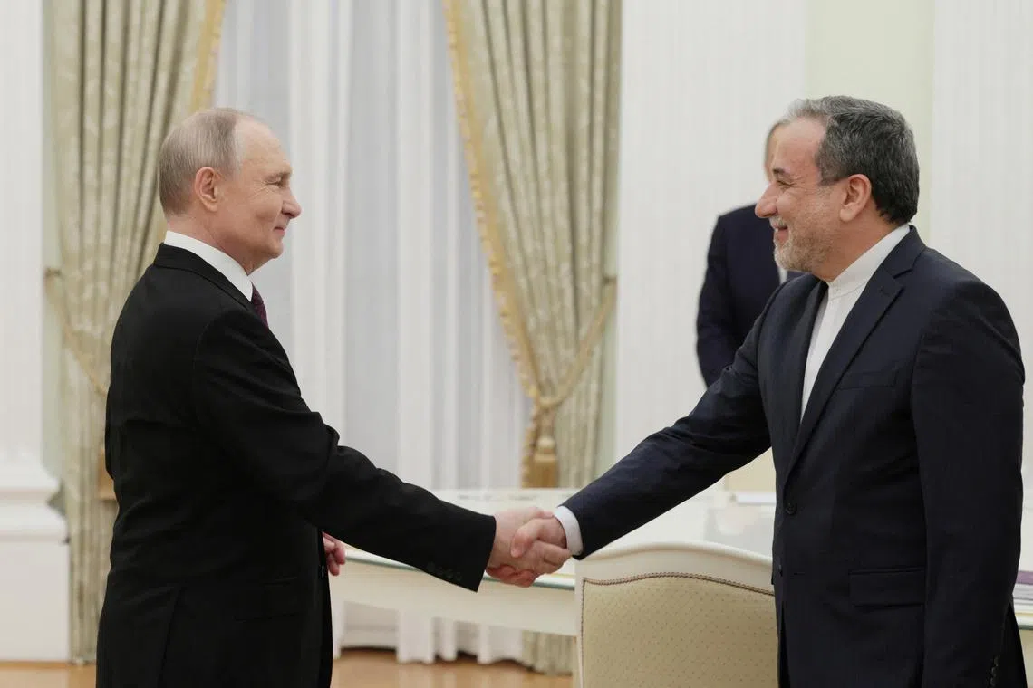 Russia's President Vladimir Putin (right) shakes hands with Iran's Foreign Minister Abbas Araqchi during a meeting in Moscow. 

