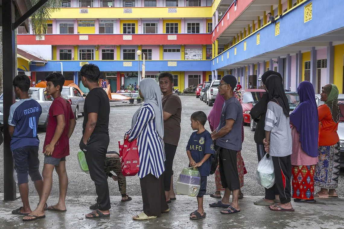 epa11045557 People affected by the flooding in Rantau Panjang queue at a shelter, in the state of Kelantan, Malaysia, 27 December 2023. More than 28,000 people in four Malaysian states have been evacuated from their homes and are seeking shelter because of worsening flood conditions due to thunderstorms, heavy rains, and strong winds.  EPA-EFE/Stringer