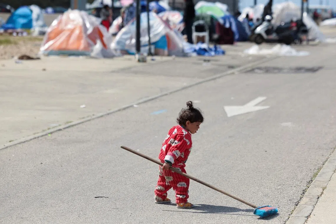 A child holding a brush next to displaced people's tents, in Beirut, Lebanon, March 16, 2026, following an escalation between Hezbollah and Israel, amid the US-Israeli conflict with Iran.