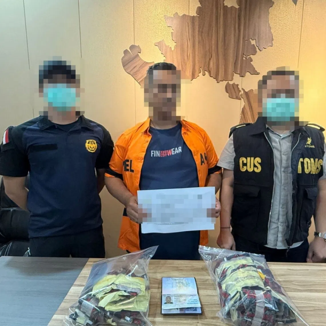 Two officers flank a man (center) suspected of trying to smuggle 148 vape pods containing etomidate from Malaysia to Indonesia on Dec 17.