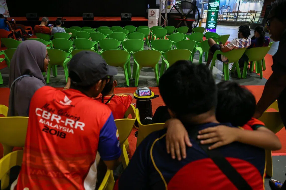 Football fans watching Spain lift the FIFA World Cup trophy on their mobile phones after the live screening at Our Tampines Hub ended and the big screen was switched off on July 20, 2026.ST PHOTO: BRIAN TEO