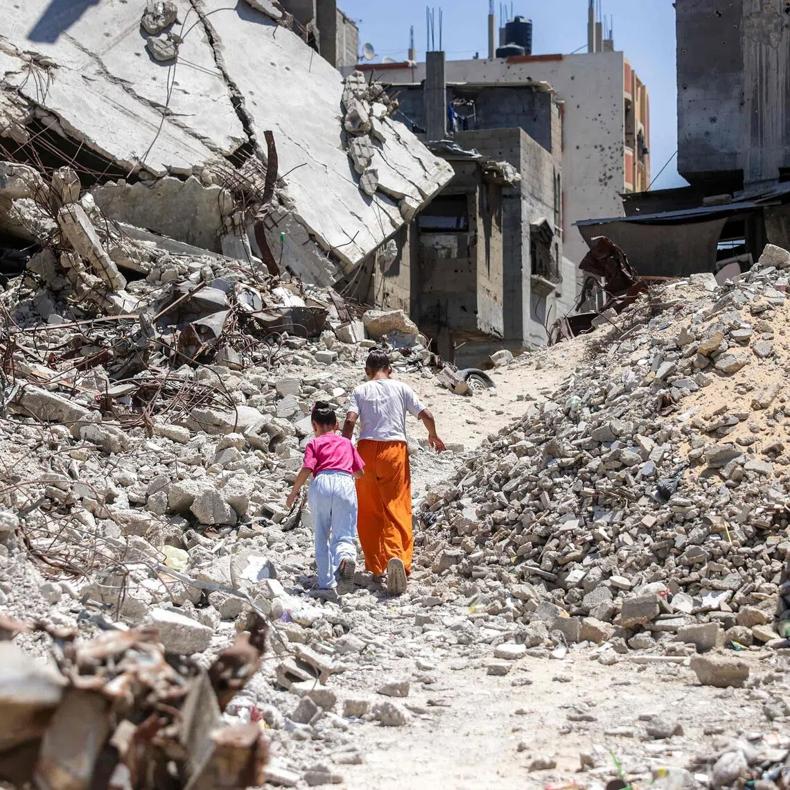 Two girls walking past the rubble of collapsed buildings in Khan Yunis, in the southern Gaza Strip, on Aug 25.