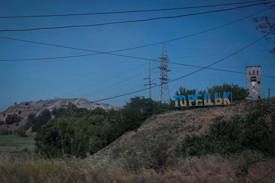 FILE PHOTO: A view shows a damaged sign that reads \"Toretsk\", panted in the colours of the Ukrainian flag, near a coal mine building and a colliery spoil, in the town of Toretsk, amid Russia's attack on Ukraine, near a front line in Donetsk region, Ukraine July 3, 2024. REUTERS/Alina Smutko/File Photo