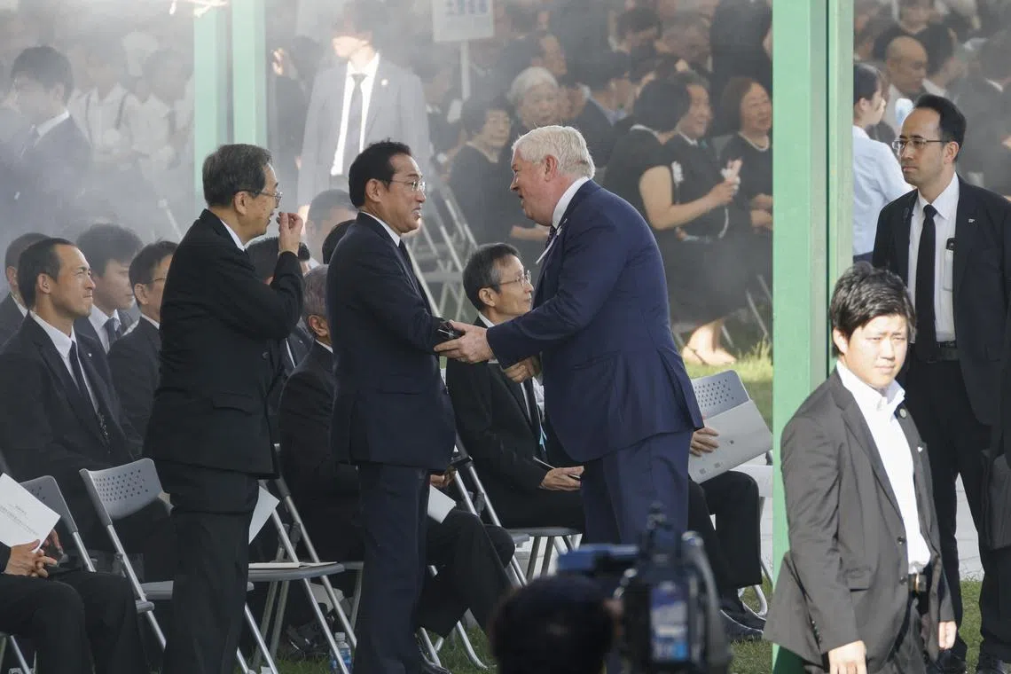 Former Japanese prime minister Fumio Kishida shaking hands with US Ambassador to Japan George Glass before the Peace Memorial Ceremony in Hiroshima on Aug 6.