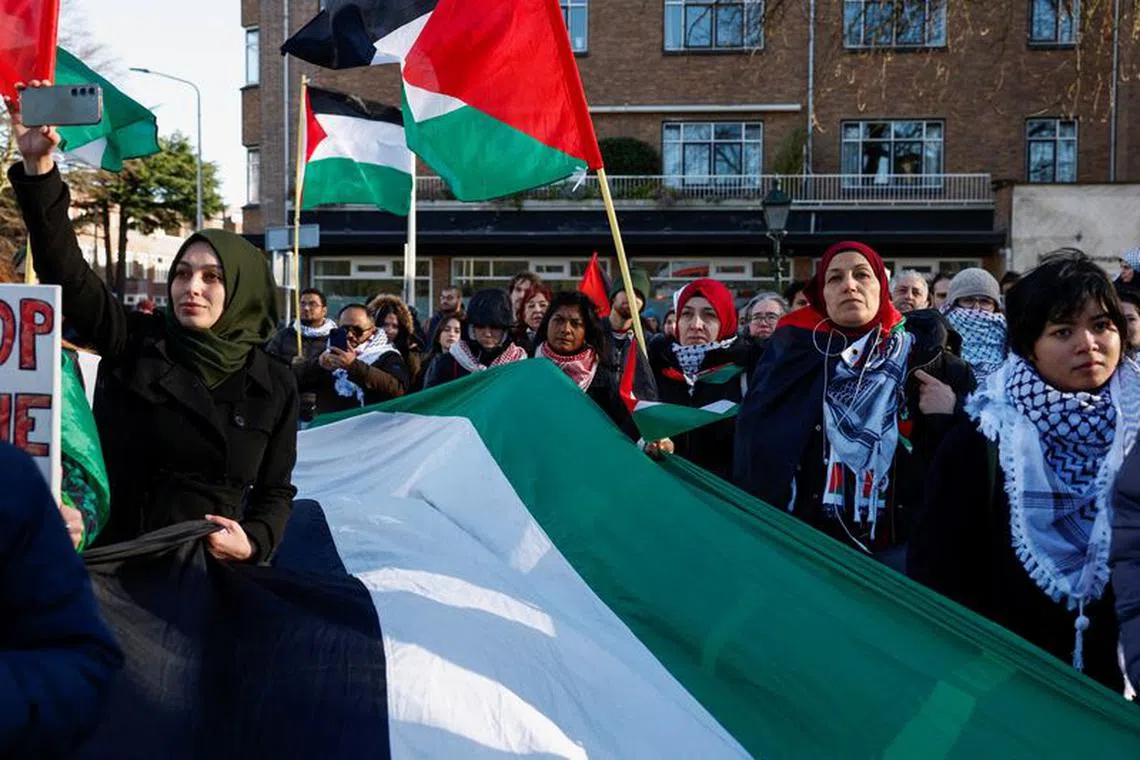 People hold flags during a pro-Palestinian demonstration outside the International Court of Justice (ICJ) as judges rule on emergency measures against Israel following accusations by South Africa that the Israeli military operation in Gaza is a state-led genocide, in The Hague, Netherlands, January 26, 2024. REUTERS/Piroschka van de Wouw