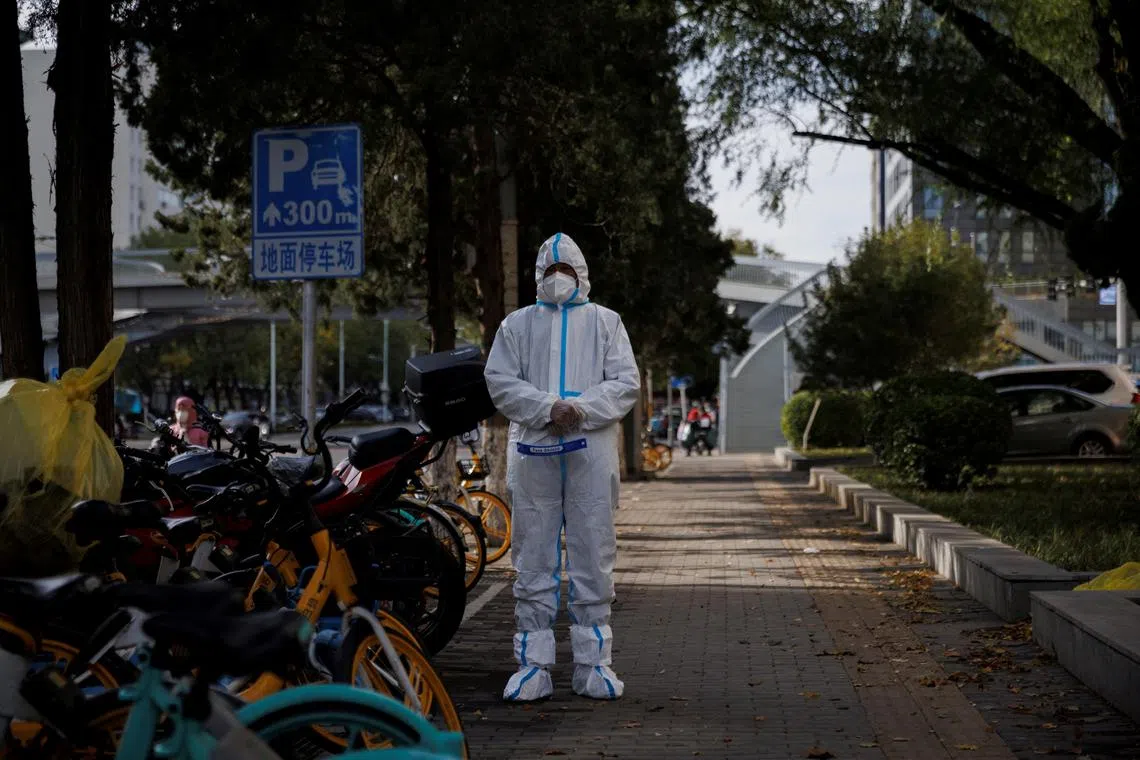 A pandemic prevention worker in a protective suit stands outside an apartment compound in Beijing on Nov 12, 2022.