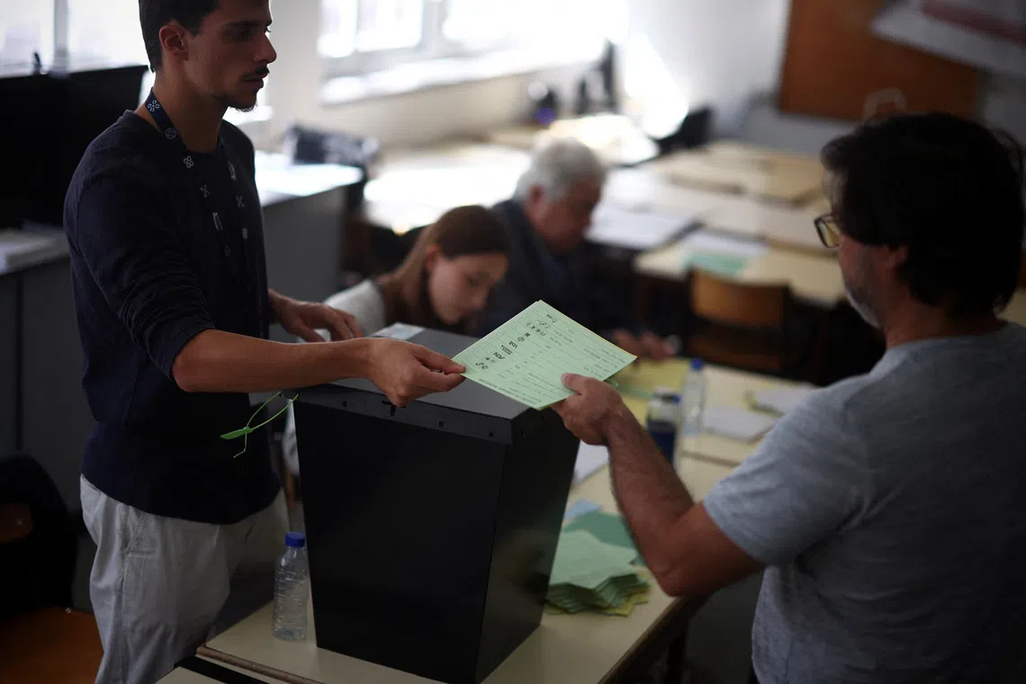 A staffer delivers a ballot to a voter at a polling station during the local election in Lisbon, Portugal, October 12, 2025. REUTERS/Pedro Nunes