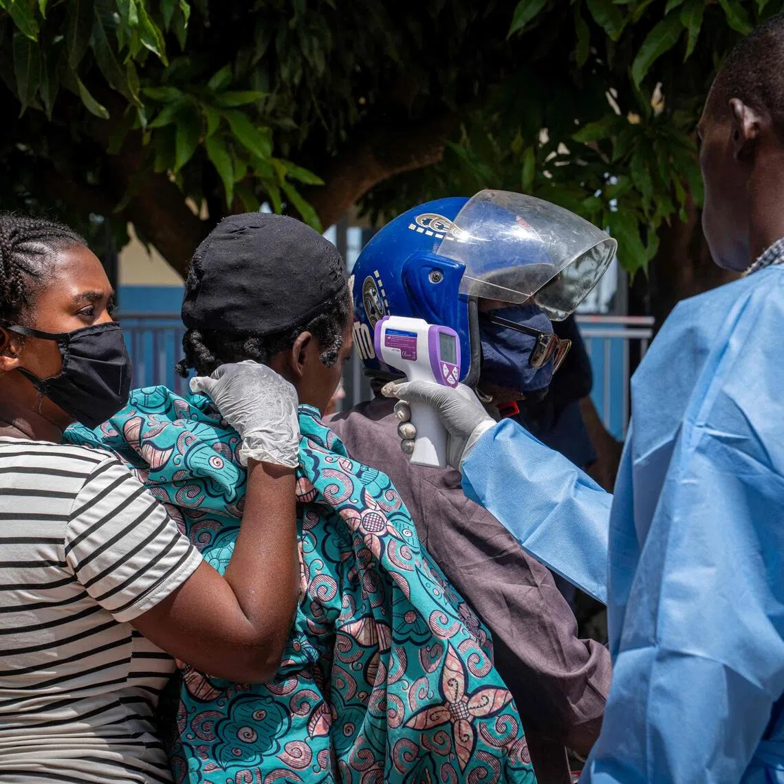 A health worker measuring the temperature of a woman suspected of having Ebola as she is transported by motorcycle taxi to Rwampara Hospital in Ituri, the Democratic Republic of the Congo, in May.