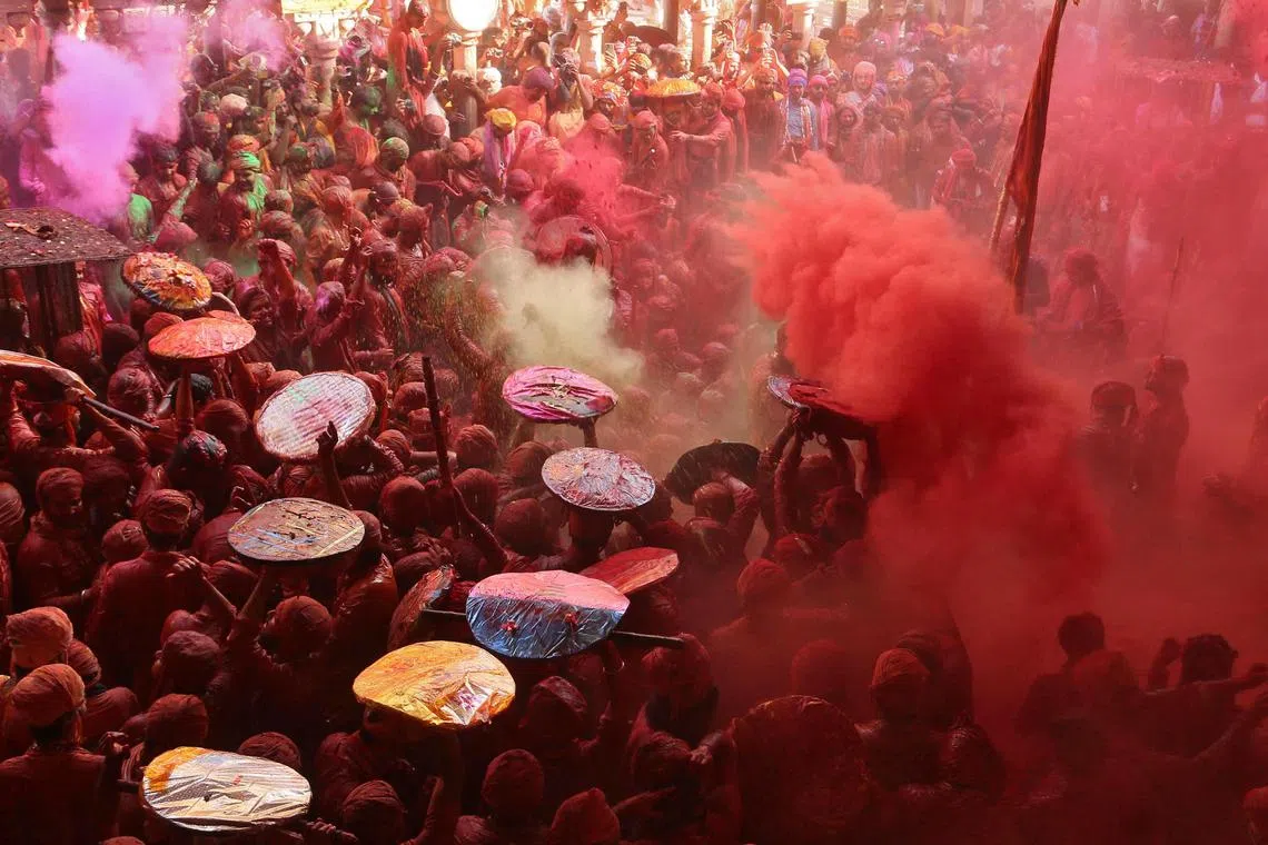 Men daubed in colours throw coloured powder at each other during "Lathmar Holi" celebrations inside a temple in the town of Barsana, Uttar Pradesh, India on Mar 18.