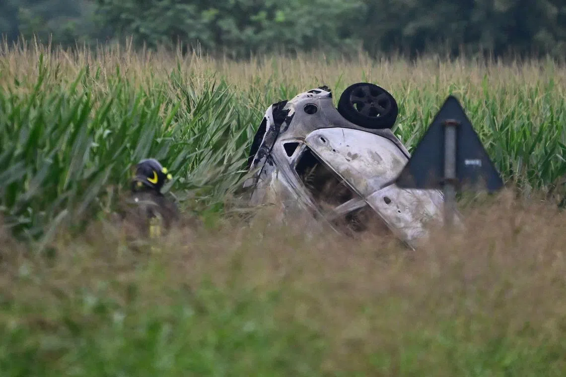 A firefighter stands near the remains of a car in which a family was travelling when it was hit by a falling military jet. 