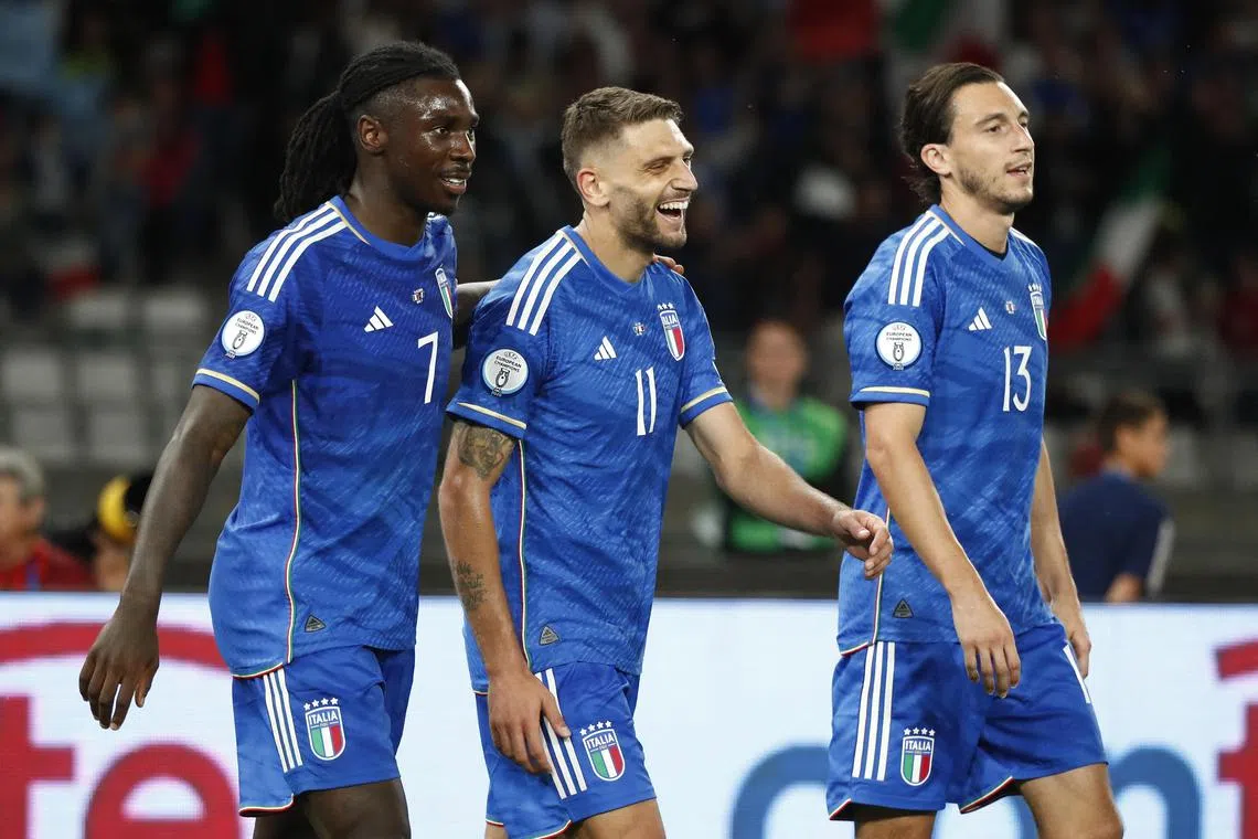 Italy's Domenico Berardi celebrates scoring their third goal with Moise Kean and Matteo Darmian.