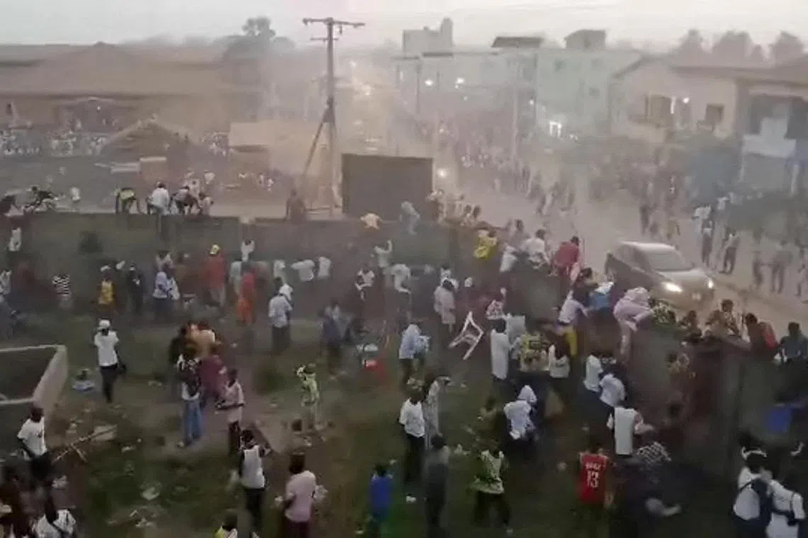 People scramble in Nzerekore, Guinea, where local officials said a deadly crush ensued at a stadium following fan clashes during a soccer match.