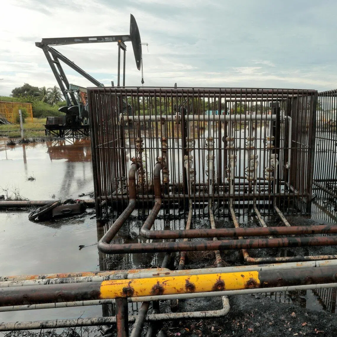Pipelines and an oil pump jack are seen in an oil field near Lake Maracaibo in Venezuela. Most analysts believe oil prices will continue to fall through 2026 amid a global supply glut.