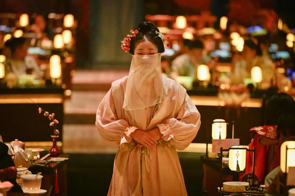 A waitress in traditional Chinese clothes waiting to serve customers at a theatrical restaurant in Beijing.