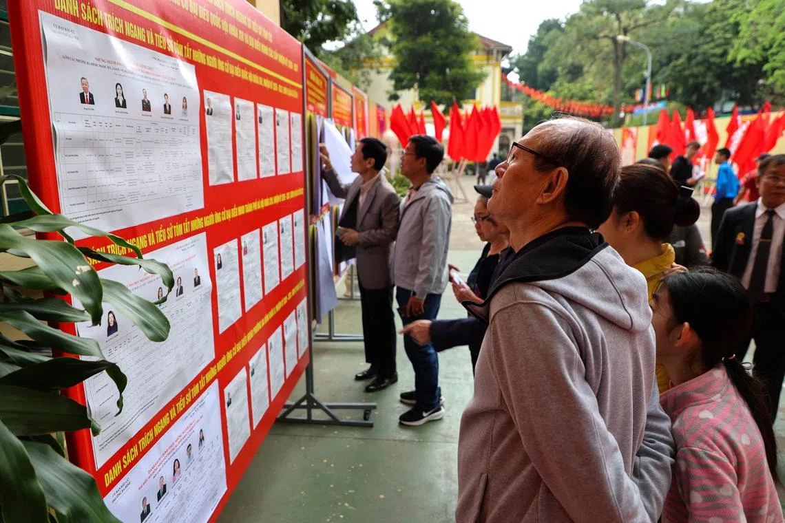 People look at a board with information about candidates outside a polling station during a parliamentary election, in Hanoi, Vietnam, March 15, 2026.