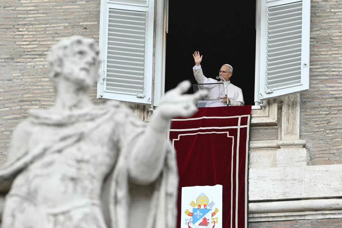 Pope Leo waves from the window of the apostolic palace overlooking St. Peter’s square during the Angelus prayer on Oct 18.