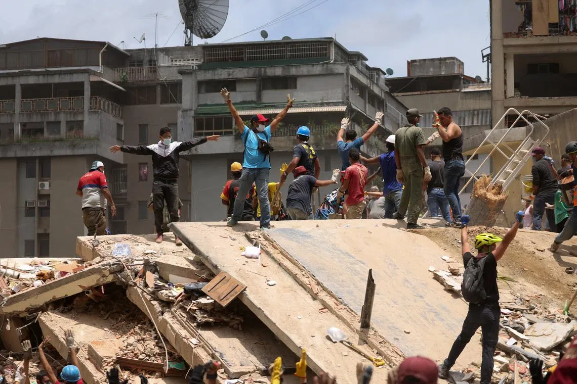 People gesture as they search for casualties amid the rubble of a collapsed building on June 25.