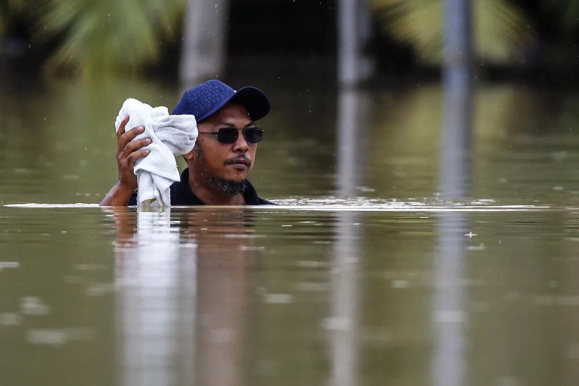 epa10501875 A man wades through a flooded area while raining in Yong Peng, Johor, Malaysia, 04 March 2023. According to state media, more than 33,000 people were evacuated in four states affected by the floods. EPA-EFE/FAZRY ISMAIL