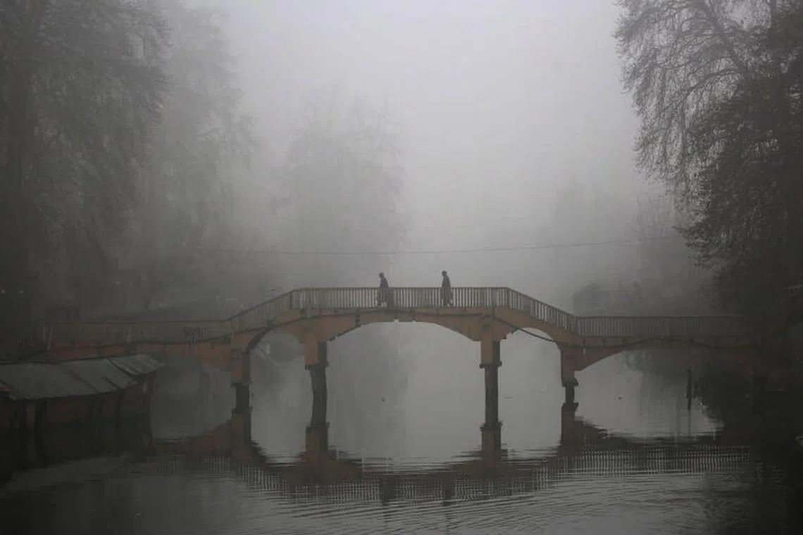 People walk across a wooden bridge during a foggy morning in Srinagar, the summer capital of Indian Kashmir on 10 January 2023. Srinagar is in the grip of severe cold and dense fog that affects daily life. PHOTO : EPA-EFE