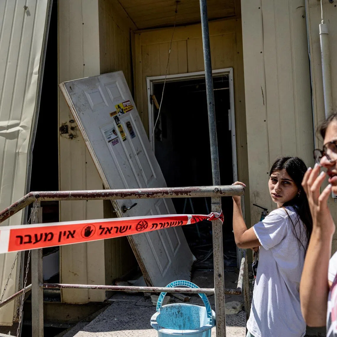 People inspect the damage caused by a nearby impact, after Iran launched missiles towards an Israeli settlement in the Israeli-occupied West Bank.