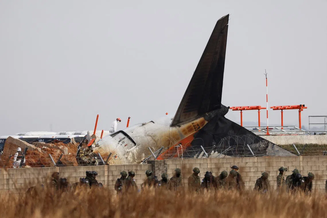 Military personnel walk at the site where an aircraft of Jeju Air went off the runway and crashed at Muan International Airport.