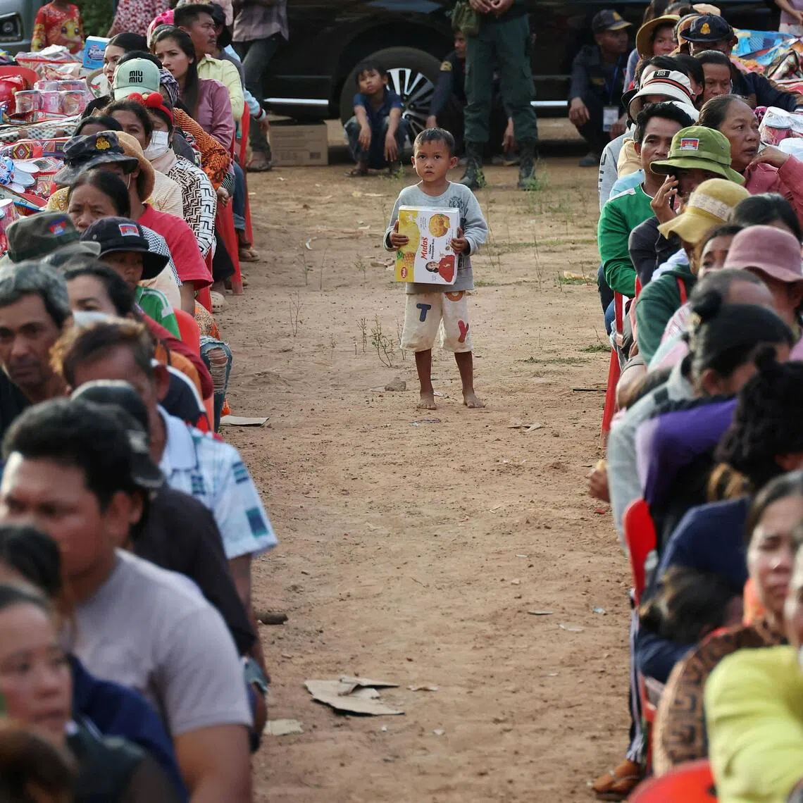 A boy stands among people waiting to collect supplies at Batthkav refugee camp in Chong Kal, Cambodia, on Dec 12.