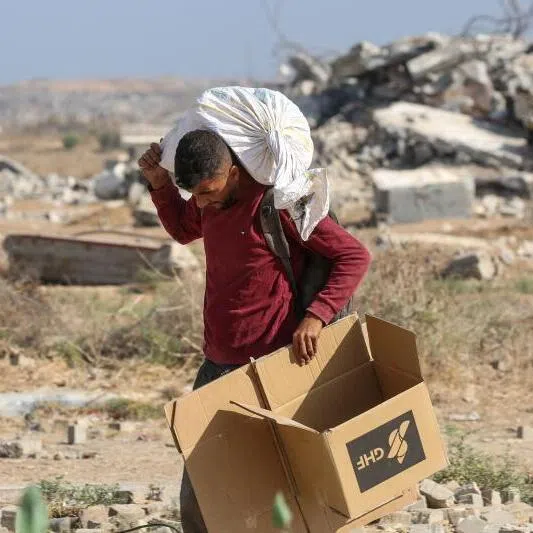 A Palestinian man walks with a bag of humanitarian aid received at a distribution centre run by the Gaza Humanitarian Foundation in Nuseirat, Gaza.