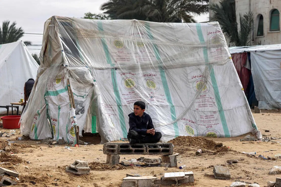 A Palestinian boy sits near a tent for displaced people in Rafah, in the southern Gaza Strip, on Feb 13.